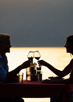 People, celebration, vacation, honeymoon and romance concept. Young couple enjoying a romantic evening dinner on the beach.